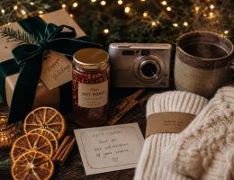 Composition festive et chaleureuse de cadeaux de Noël originaux : bocal gourmand, appareil photo vintage, tasse réconfortante et emballages naturels
