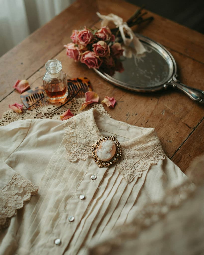 La broche : le détail qui change tout (guide complet pour la porter avec style, vintage & strass) Broche camée sculptée montée sur le col en dentelle d'une blouse ivoire inspiration victorienne, ambiance romantique vintage