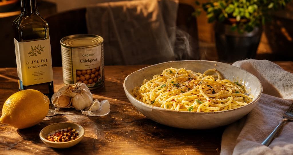 Bol de pâtes simple à l'ail et huile d'olive entouré d'ingrédients de placard basiques