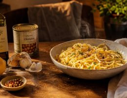 Bol de pâtes simple à l'ail et huile d'olive entouré d'ingrédients de placard basiques