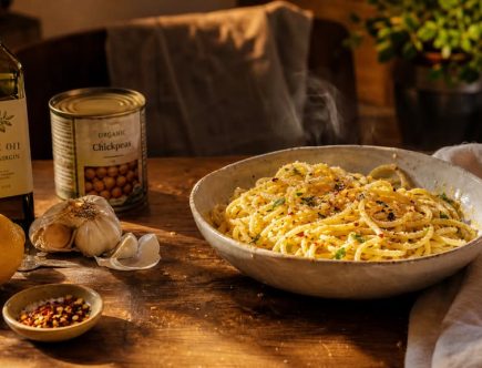 Bol de pâtes simple à l'ail et huile d'olive entouré d'ingrédients de placard basiques