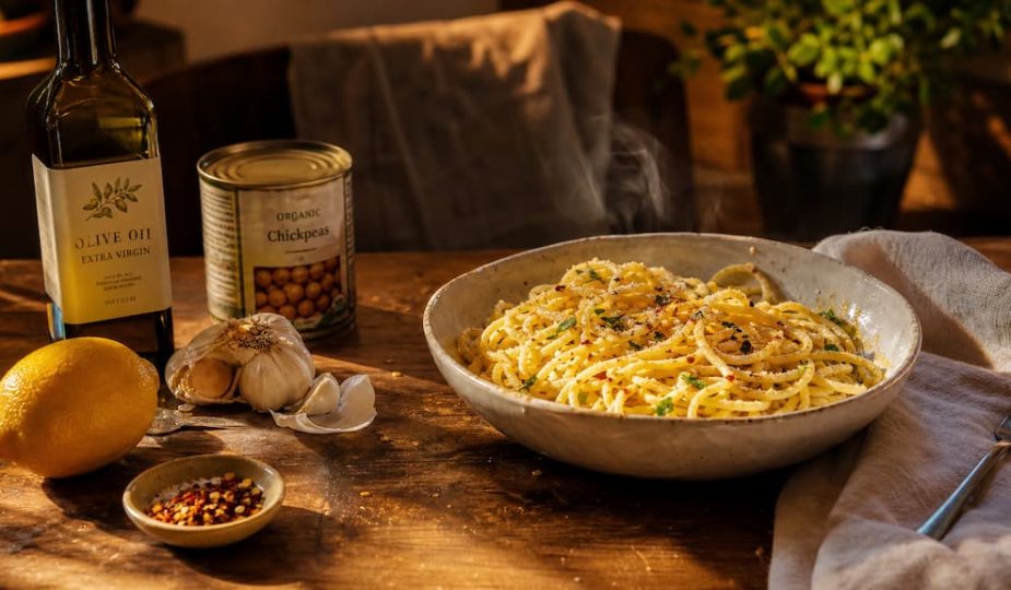 Bol de pâtes simple à l'ail et huile d'olive entouré d'ingrédients de placard basiques