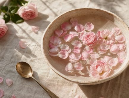 Composition boho-chic avec bol en céramique rempli d'eau et de pétales de rose flottants sur lin clair